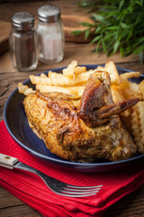 Roasted chicken with french fries on a plate.