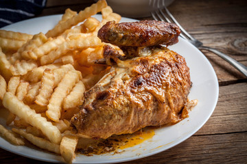 Roasted chicken with french fries on a plate.