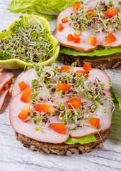 Sandwiches with lettuce, ham and broccoli sprouts.