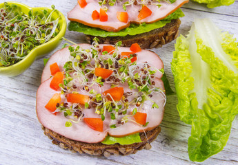 Sandwiches with lettuce, ham and broccoli sprouts.