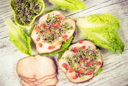Sandwiches with lettuce, ham and broccoli sprouts.