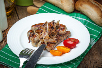Fried Fried white sausages with onion on the plate.white sausages in a cast iron skillet.