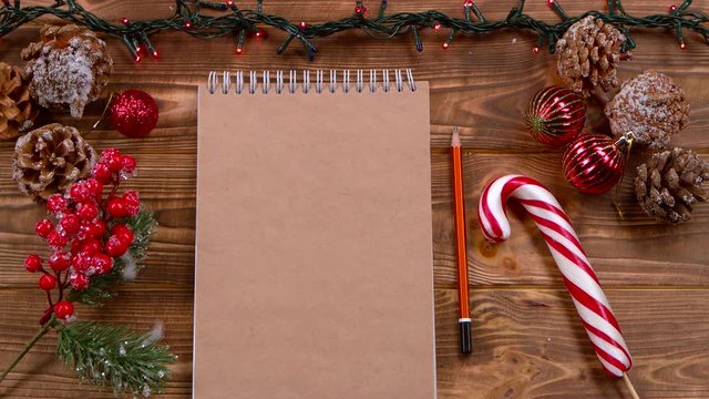 Mockup Notebook and pencil lie on the table, Christmas toys and garlands around. Top view