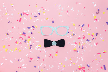Table top view aerial image of beautiful carnival mask or photo booth props background.Flat lay glasses & gentleman bow tie on modern rustic pink paper at office desk studio.space for creative design.