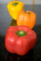 A red, orange and yellow bell pepper arranged in a row