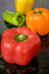 Peppers arranged in a row on black granite counter
