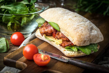 Ciabatta sandwich with arugula salad, bacon and yellow cheese. © Arkadiusz Fajer