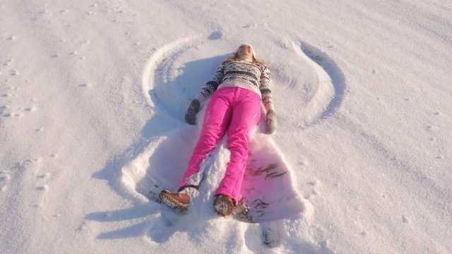 Cheerful Young Woman On A Sunny Day In The Winter Making Snow Angels Slow Motion