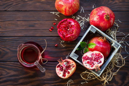 Freshly squeezed pomegranate fruit juice and ripe pomegranate on a wooden table. The concept of nutrition for superfoods and health or detoxification. Flat lay. Top view with copy space.