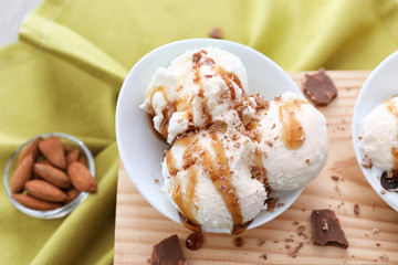 Tasty vanilla ice-cream balls with caramel topping in bowl on board