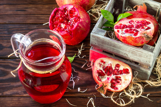 Freshly squeezed pomegranate fruit juice and ripe pomegranate on a wooden table. The concept of nutrition for superfoods and health or detoxification.