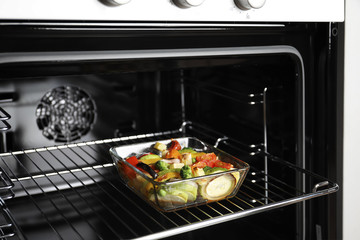 Glass baking dish with vegetables in oven