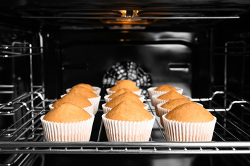 Tasty cupcakes on baking rack in oven