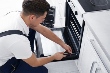 Fototapeta na wymiar Young man repairing oven in kitchen