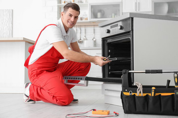 Young man repairing oven in kitchen