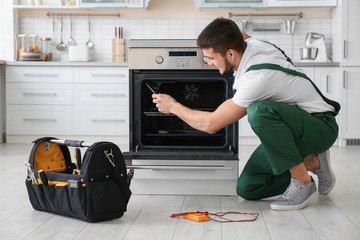 Young man repairing oven in kitchen