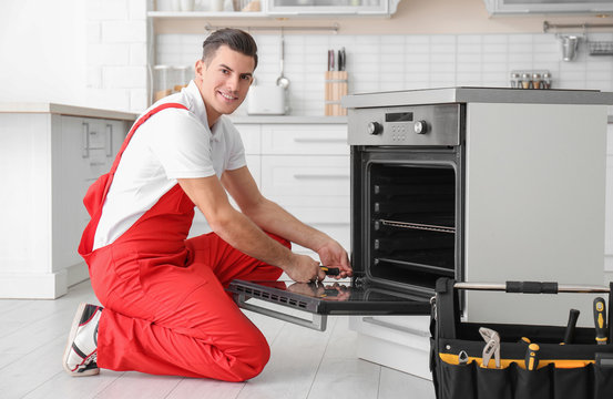 Young man repairing oven in kitchen