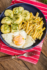 Fried egg served with potatoes and yellow beans.