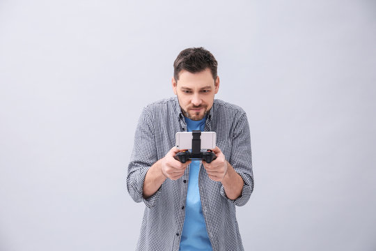Emotional man with video game controller for smartphone on grey background
