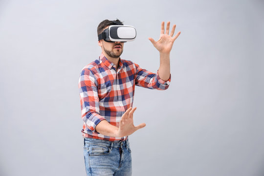 Man with virtual reality headset on grey background