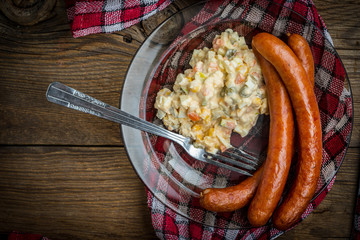 Thin sausages with vegetable salad on plate.