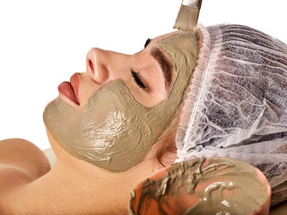 Mud facial mask of woman in spa salon. Massage with clay full face. Girl on with therapy room. Healing clay for face. Spring discounts for visiting spa salon.