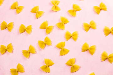 Yellow pasta on pastel pink background close up macro.