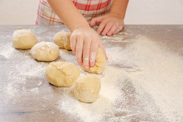 Unleavened dough for tortillas with flour and hand on kitchen table. Cooking burrito.