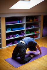 Young attractive smiling woman practicing yoga, in gym