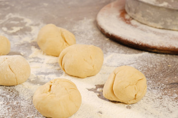 Unleavened dough for tortillas with flour and hand on kitchen table. Cooking burrito.