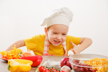 Healthy eating. Happy child prepares and eats vegetables in kitchen