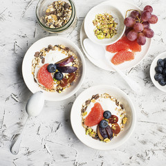 Seasonal healthy breakfast: yoghurt, chocolate granola, pink grapefruit, grapes, pistachios. Top view. Copy space. flat lay