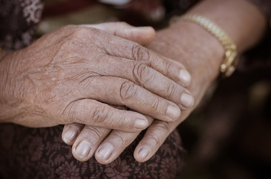 Hands Asian elderly woman grasps her hand on lap, pair of elderly wrinkled hands and Traces of hard work, World Kindness older and Adult care  concept. Senior citizen is common euphemism