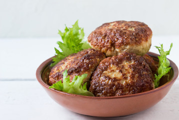 Homemade cutlets and lettuce leaves on a plate.