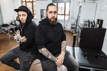 Portrait of two professional creative tattoo masters