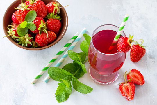Freshly squeezed strawberry berry juice and fresh strawberry berries on a gray stone or slate background. The concept of nutrition for superfoods and health or detoxification. Copy space.