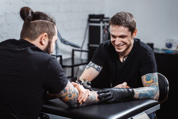master tattooist makes a tattoo on the skin of the client with special equipment
