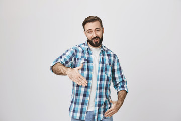 Funny adult bearded man with trendy haircut and plaid shirt making robot gestures or reading rap standing over gray background. Man tries to impress woman with modern poetry.