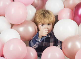 Fototapeta na wymiar Boy at party showing thumbs up. Beautiful child among pink balloons is happy with gifts and happy childhood. Kids closeup face. White and pink balls decoration on event. Opening children toys shop