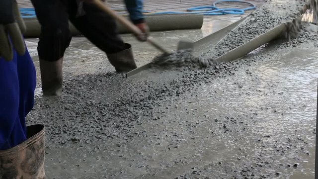 Close up and slow motion footage of  mixed concrete from truck. Manual concrete worker with a shovel at house construction site.