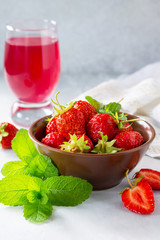 Freshly squeezed strawberry berry juice and fresh strawberry berries on a gray stone or slate background. The concept of nutrition for superfoods and health or detoxification. Copy space.