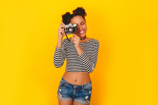 Young african woman isolated on yellow wall studio teen style taking photos