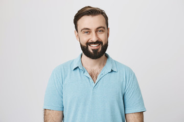 Handsome bearded man in blue t shirt on a white background. Bartender invites visitors with a wide smile on his face to have a drink or two. Joy and happiness concept. Good mood is a key to success