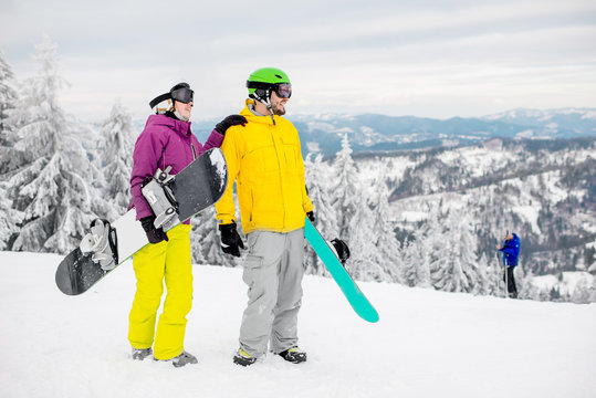 Young couple walking with snowboards during the winter vacation on the snowy mountains