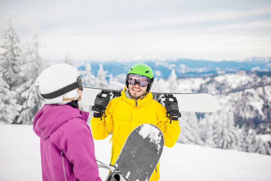 Young couple in winter sports clothes talking together with snowboards during the winter vacation on the snowy mountains