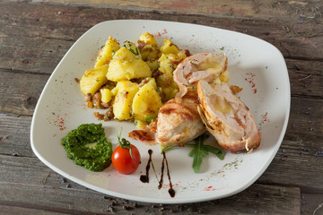 Roulade of stuffed chicken with potatoes. On a wooden background. rustic food