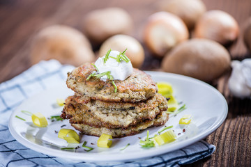 stacked fried potato cakes on white plate with sour cream, spring onion and chives