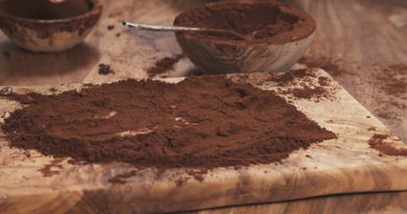 female hands making truffles in cocoa powder on board