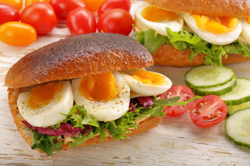 Sandwich with egg and vegetables on wooden background