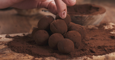 female hands making truffles in cocoa powder on board